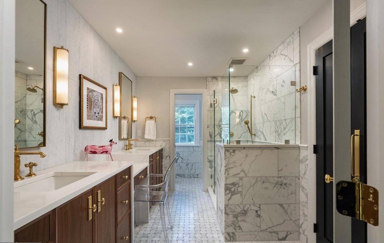 Bathroom with book-matched marble, a walnut double vanity and glass shower enclosure