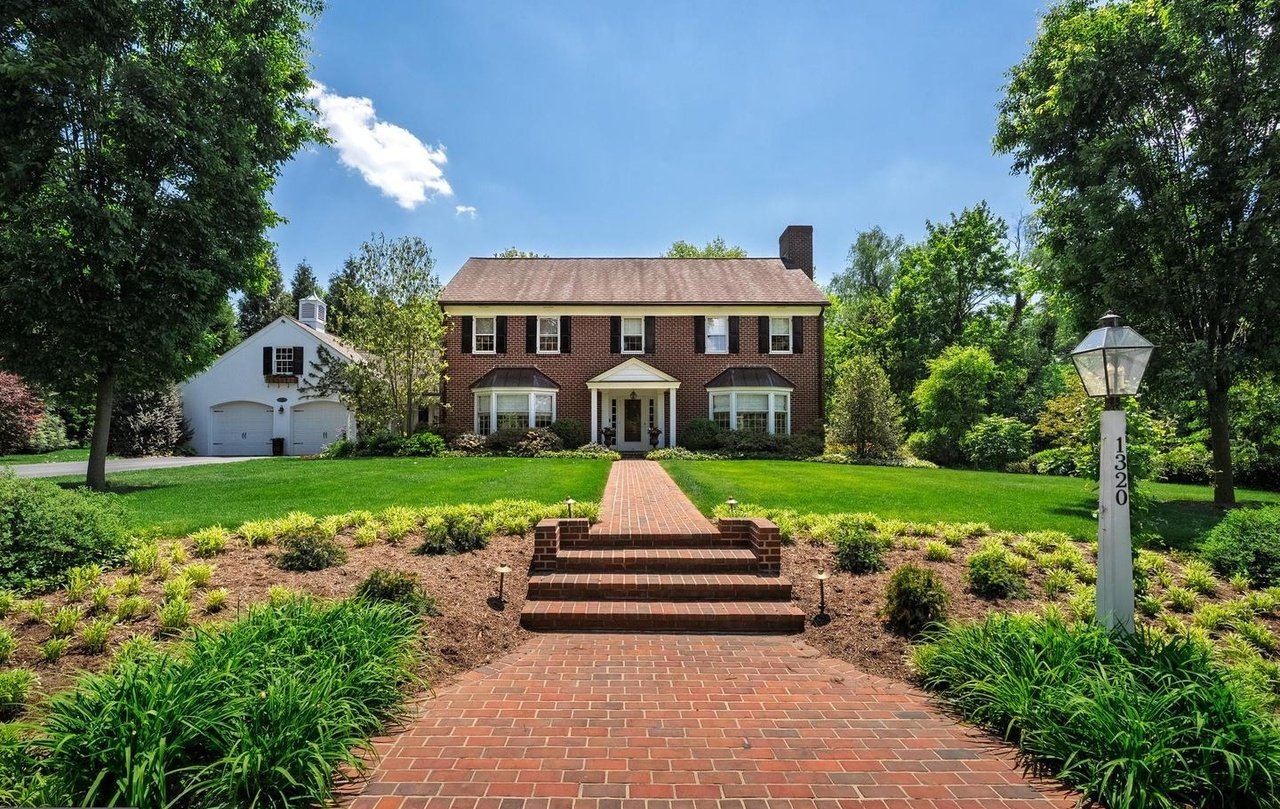 Front of 1320 Homestead Lane: a brick Georgian colonial with a brick walk, mature trees and a white carriage-house garage