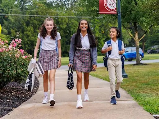 Three students in uniform walking along a sidewalk to Lancaster Country Day School
